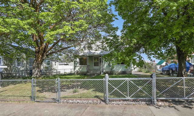 view of front of home with a fenced front yard, a gate, and a front lawn