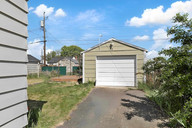 detached garage featuring fence and driveway