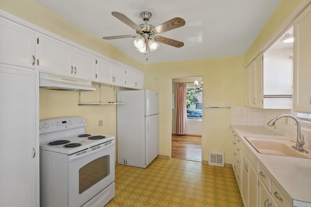 kitchen featuring a sink, white appliances, light countertops, under cabinet range hood, and visible vents