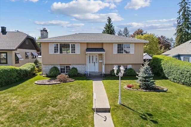 bi-level home featuring a chimney, roof with shingles, and a front lawn