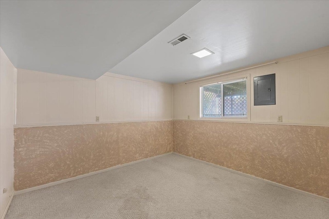 carpeted empty room featuring baseboards, visible vents, and electric panel