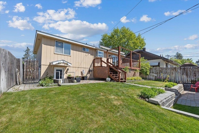 rear view of property featuring a lawn, a wooden deck, a fenced backyard, and stairs