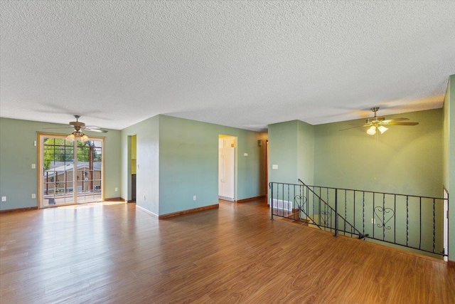 unfurnished room featuring baseboards, ceiling fan, a textured ceiling, and wood finished floors