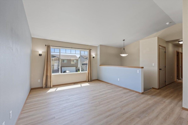unfurnished room featuring baseboards, wood finished floors, and lofted ceiling