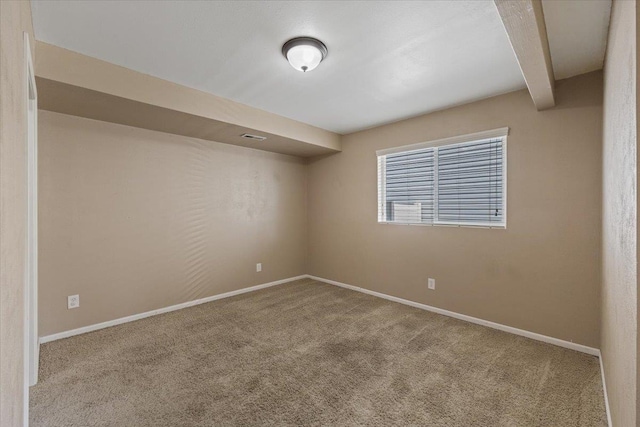 carpeted empty room featuring beamed ceiling and baseboards