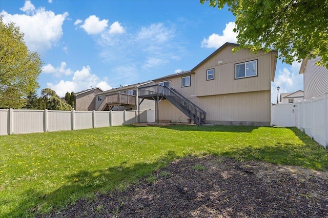back of house with a fenced backyard, a wooden deck, a lawn, and stairway