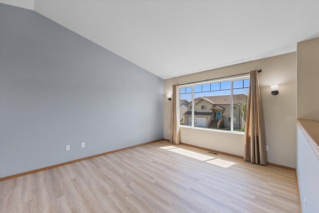 empty room with light wood-style floors, vaulted ceiling, and visible vents