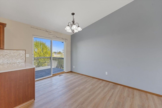 unfurnished dining area with an inviting chandelier, baseboards, light wood finished floors, and visible vents