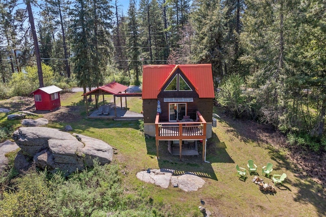 rear view of property with an outdoor structure, a shed, a yard, and a deck