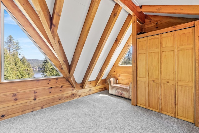 additional living space with wood walls, lofted ceiling with beams, light carpet, and a mountain view