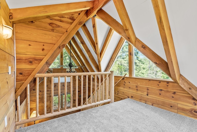 additional living space with carpet flooring, lofted ceiling, and wood walls