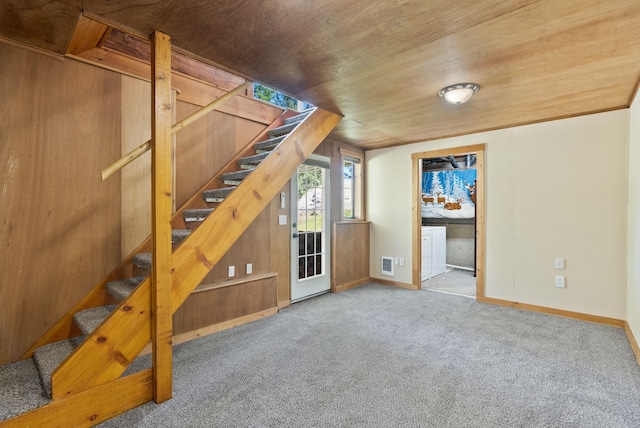 unfurnished living room with visible vents, stairway, baseboards, wooden ceiling, and carpet flooring
