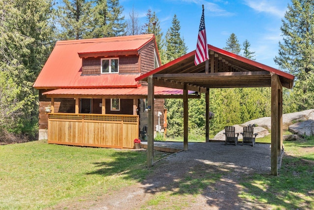 exterior space with a detached carport, dirt driveway, metal roof, and a front yard