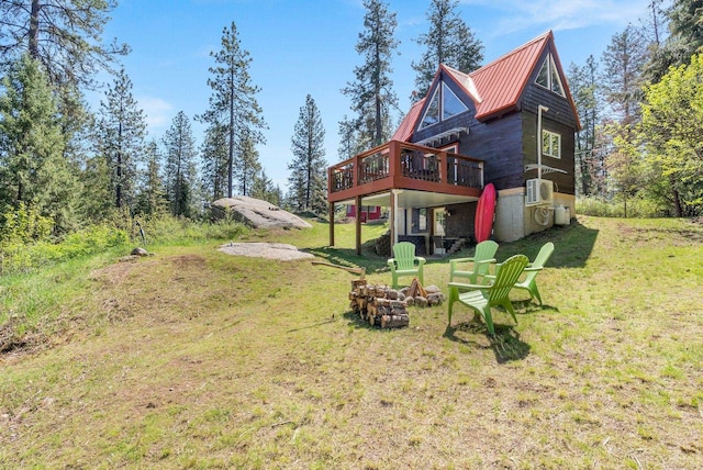 rear view of property with a lawn, a standing seam roof, a deck, and metal roof
