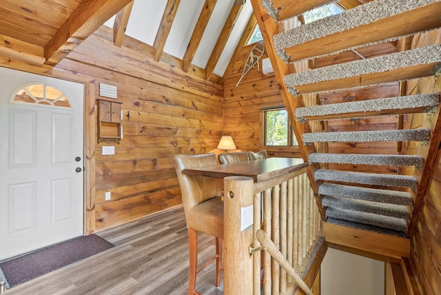 interior space featuring wooden walls, lofted ceiling with beams, and wood finished floors