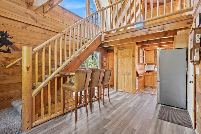 stairway with wood walls, a towering ceiling, and wood finished floors