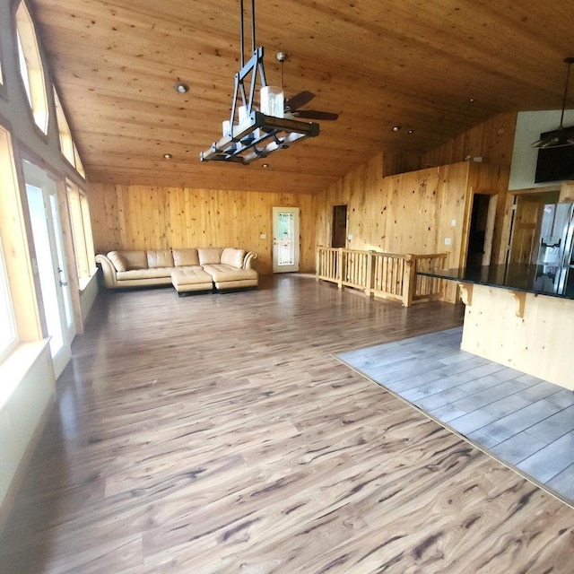 unfurnished living room with high vaulted ceiling, wood walls, wooden ceiling, and wood finished floors