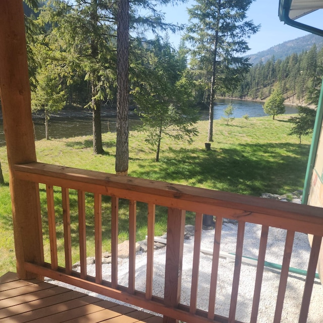 deck with a water and mountain view, a yard, and a forest view