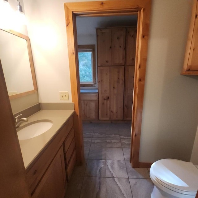 bathroom with toilet, marble finish floor, and vanity