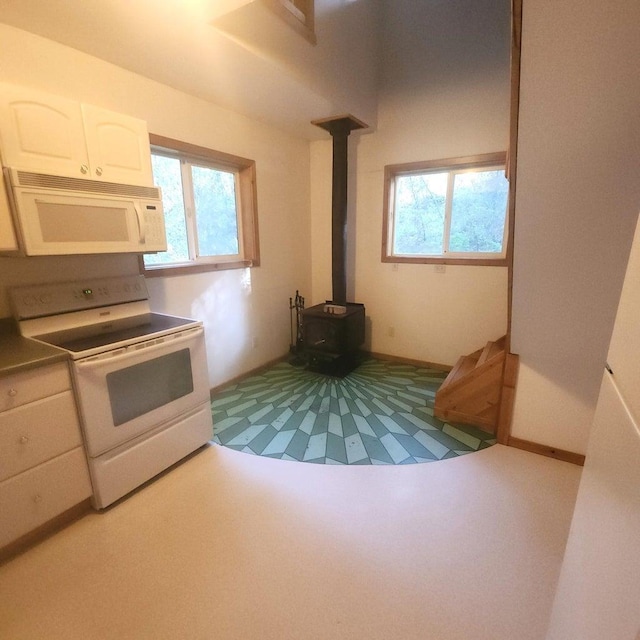 kitchen with white appliances, white cabinets, and a wood stove
