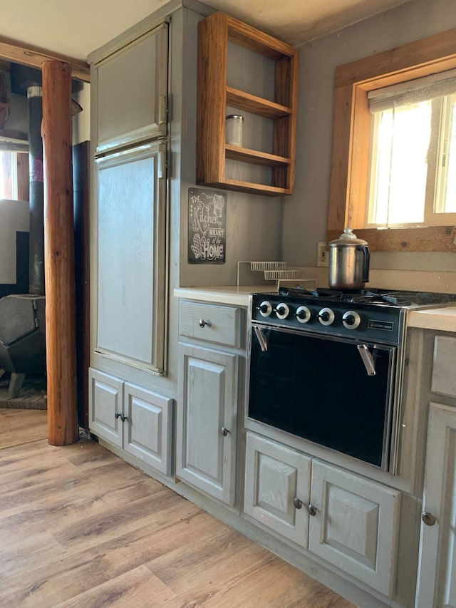 kitchen with light countertops, light wood-style floors, open shelves, and range with gas cooktop