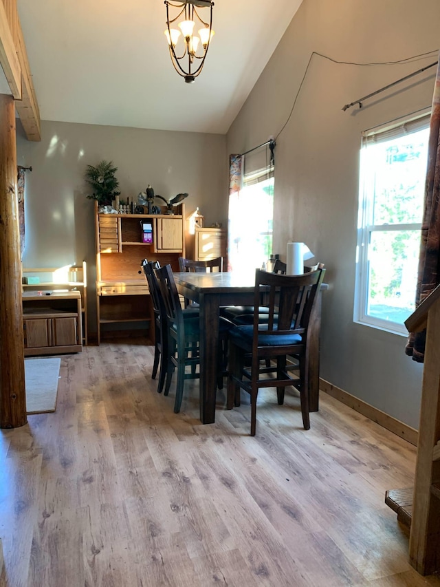 dining space with an inviting chandelier, light wood-style flooring, and lofted ceiling
