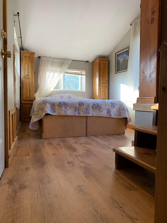 bedroom featuring lofted ceiling and light wood-type flooring