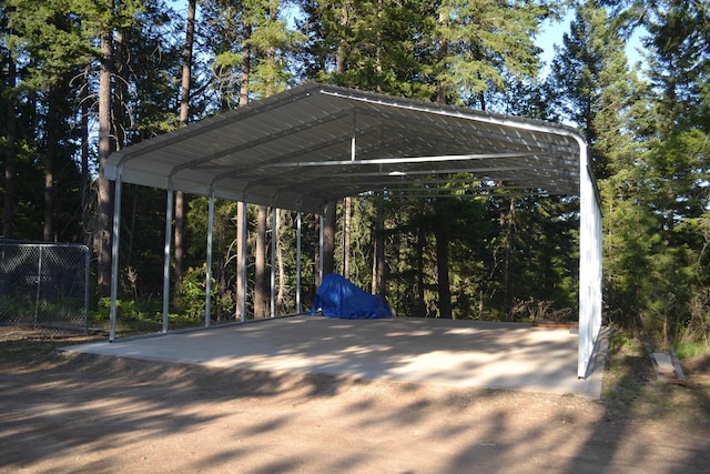 view of vehicle parking featuring fence, driveway, and a detached carport