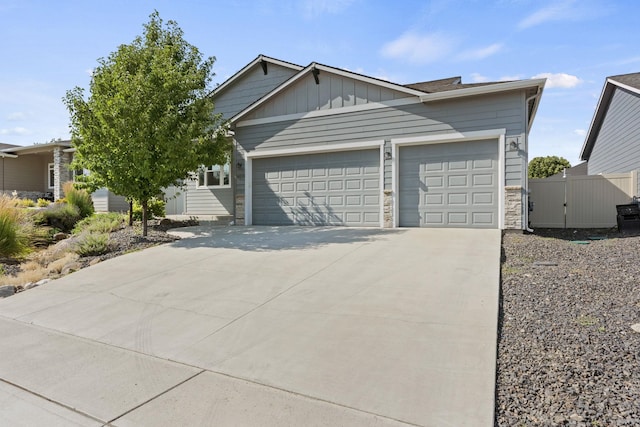 ranch-style home with fence, stone siding, board and batten siding, an attached garage, and driveway