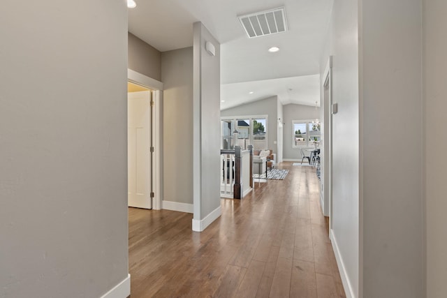 corridor with visible vents, wood-type flooring, baseboards, recessed lighting, and vaulted ceiling