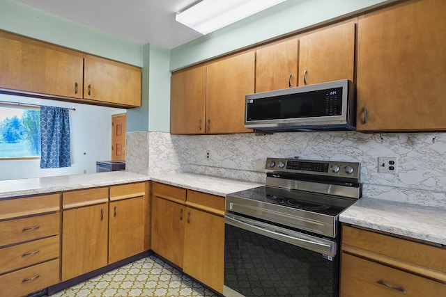 kitchen with stainless steel appliances, brown cabinetry, decorative backsplash, and light floors