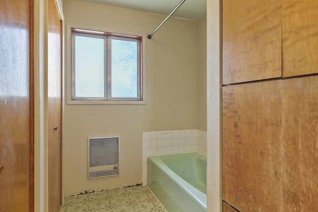 bathroom featuring a garden tub, heating unit, and tile patterned flooring