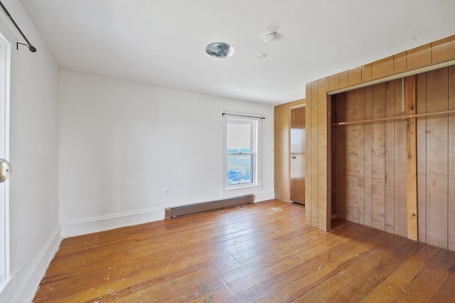 unfurnished bedroom with baseboards, a baseboard radiator, a closet, and hardwood / wood-style flooring