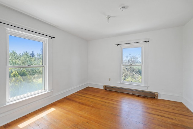 empty room featuring baseboards, light wood-style flooring, and a baseboard heating unit