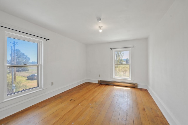 empty room featuring light wood-style floors, baseboards, and a baseboard heating unit
