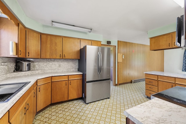 kitchen with light countertops, a baseboard heating unit, appliances with stainless steel finishes, and light floors