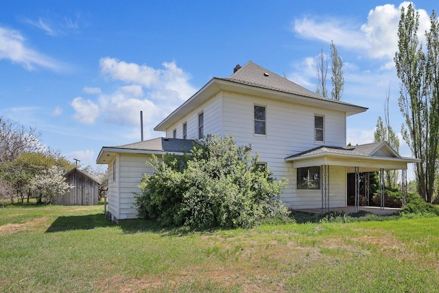 back of house with a lawn and roof with shingles