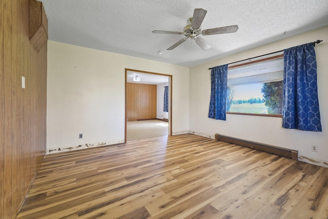empty room with a ceiling fan, light wood-style flooring, a textured ceiling, and a baseboard heating unit