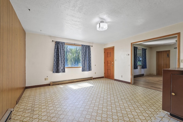 spare room featuring wooden walls, baseboards, and a baseboard heating unit