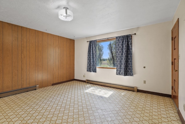 carpeted spare room featuring wooden walls, baseboards, and baseboard heating