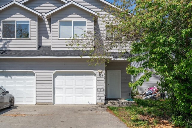 view of front of property featuring concrete driveway, a shingled roof, and a garage