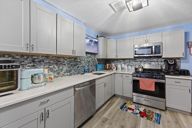 42480 N State Route 25th Hwy, Davenport, WA 99122 - kitchen featuring a sink, stainless steel appliances, backsplash, gray cabinetry, and light wood-style floors