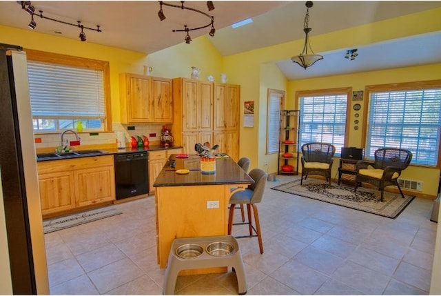 kitchen featuring a sink, black dishwasher, a breakfast bar, track lighting, and dark countertops