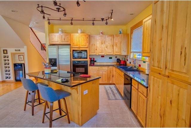 kitchen with light tile patterned floors, a breakfast bar, a sink, a kitchen island, and black appliances
