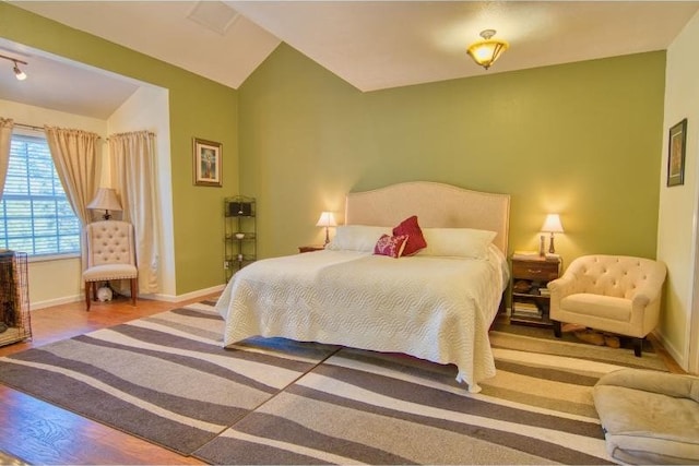 bedroom with wood finished floors, baseboards, and lofted ceiling