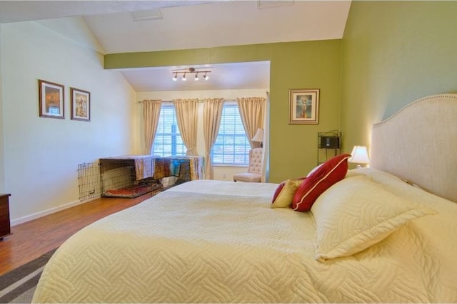 bedroom with baseboards, wood finished floors, and lofted ceiling