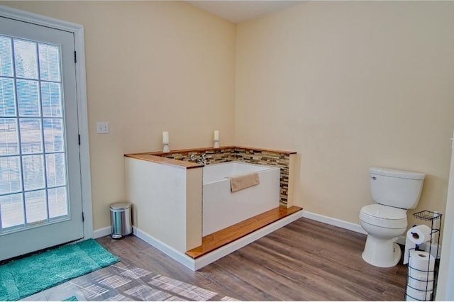 full bathroom featuring a bath, a wealth of natural light, wood finished floors, and toilet