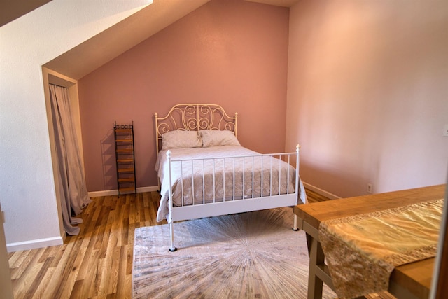 bedroom featuring baseboards, lofted ceiling, and wood finished floors