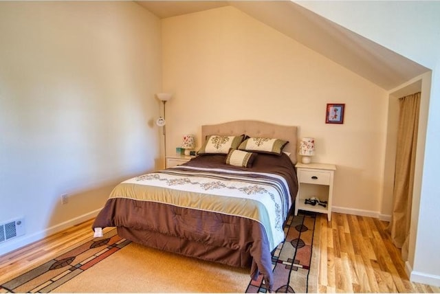 bedroom featuring lofted ceiling, baseboards, visible vents, and wood finished floors