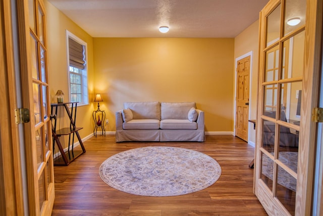 living area with baseboards, french doors, and wood finished floors